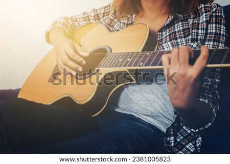 Young hipster woman playing a guitar.