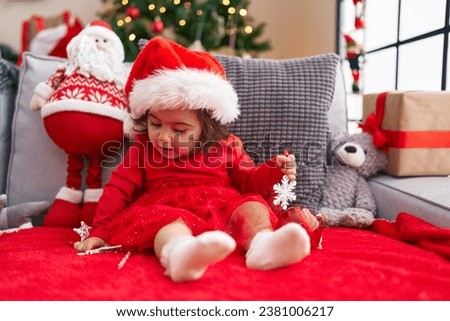 Adorable hispanic girl sitting on sofa by christmas tree at home