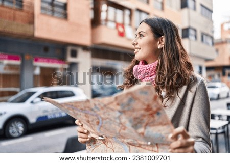 Young beautiful hispanic woman smiling confident holding city map at street