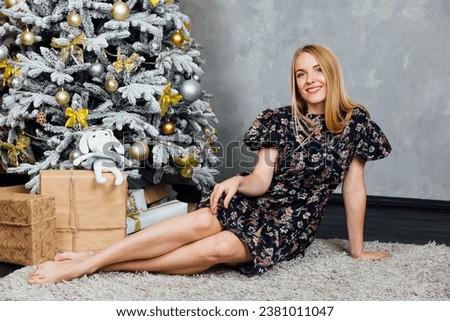 blonde woman sitting with gifts near Christmas tree New Year holiday Christmas