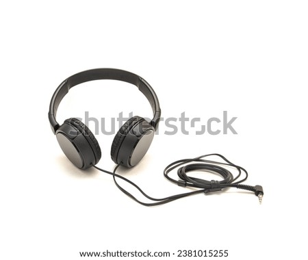 Top view black wired headphone with swiveling earcup foam cushions, L-shaped stereo mini plug 3.5mm isolated on white background, corded kids headphones, technology accessories. Sound gadget