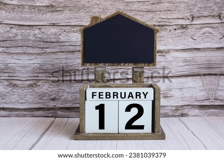 Chalkboard with calendar date on white cube block on wooden table.