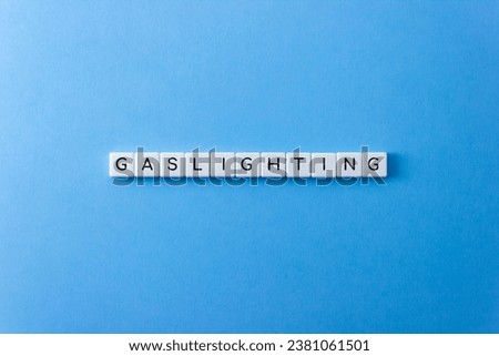 Word Gaslighting on plastic blocks on blue background. Psychological violence concept Royalty-Free Stock Photo #2381061501