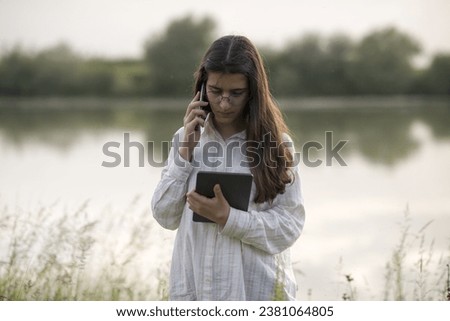 Young business woman having a job interview on the phone, doing business analysis, in the garden of the office, by the lake Royalty-Free Stock Photo #2381064805