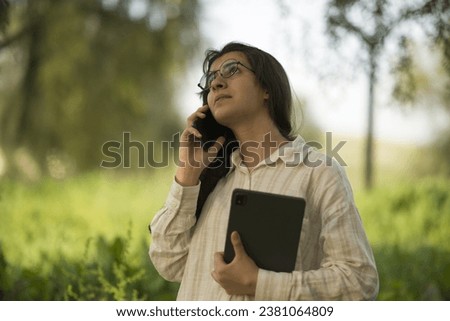Young business woman having a job interview on the phone, doing business analysis, in the garden of the office, by the lake Royalty-Free Stock Photo #2381064809