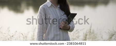Young business woman having a job interview on the phone, doing business analysis, in the garden of the office, by the lake Royalty-Free Stock Photo #2381064811