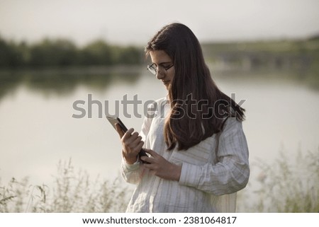 Young business woman having a job interview on the phone, doing business analysis, in the garden of the office, by the lake Royalty-Free Stock Photo #2381064817