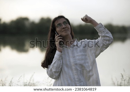 Young business woman having a job interview on the phone, doing business analysis, in the garden of the office, by the lake Royalty-Free Stock Photo #2381064819