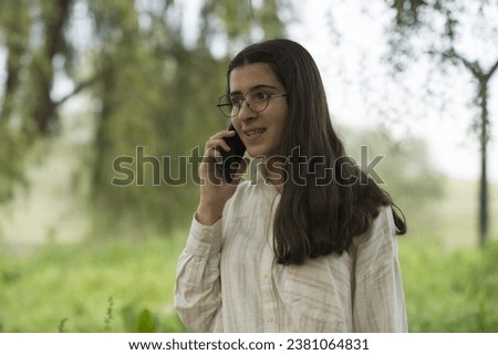 Young business woman having a job interview on the phone, doing business analysis, in the garden of the office, by the lake Royalty-Free Stock Photo #2381064831