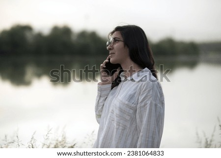 Young business woman having a job interview on the phone, doing business analysis, in the garden of the office, by the lake Royalty-Free Stock Photo #2381064833