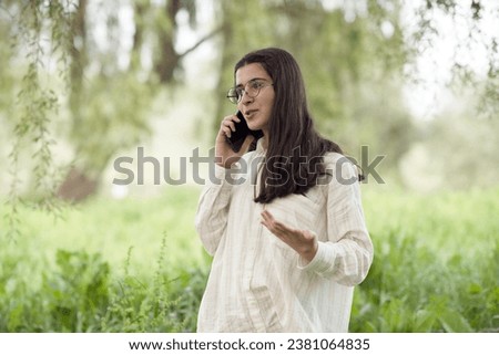 Young business woman having a job interview on the phone, doing business analysis, in the garden of the office, by the lake Royalty-Free Stock Photo #2381064835