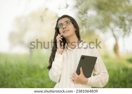 Young business woman having a job interview on the phone, doing business analysis, in the garden of the office, by the lake Royalty-Free Stock Photo #2381064839