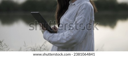 Young business woman having a job interview on the phone, doing business analysis, in the garden of the office, by the lake Royalty-Free Stock Photo #2381064841