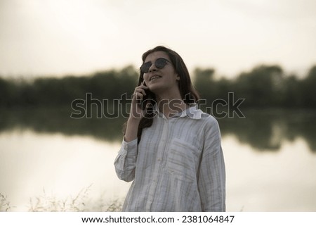 Young business woman having a job interview on the phone, doing business analysis, in the garden of the office, by the lake Royalty-Free Stock Photo #2381064847