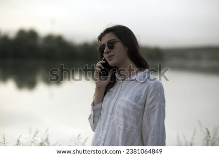 Young business woman having a job interview on the phone, doing business analysis, in the garden of the office, by the lake Royalty-Free Stock Photo #2381064849