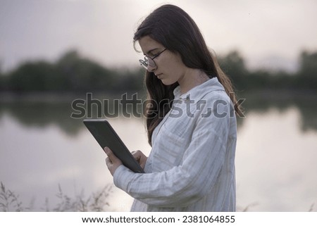 Young business woman having a job interview on the phone, doing business analysis, in the garden of the office, by the lake Royalty-Free Stock Photo #2381064855