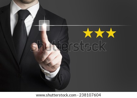 businessman in black suit pushing button three rating stars