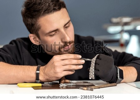 A jeweler in the workshop working on a bracelet. Close-up of a bracelet in the hands of a jeweler Royalty-Free Stock Photo #2381076445