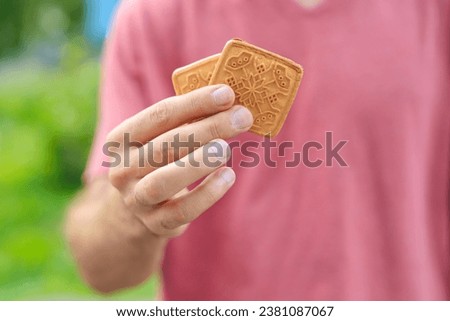 Guy's hand holds cookies, snack and fast food concept. Selective focus on hands with blurred background and copy space for text.