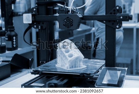 Prototype of car engine printed on 3D printer from molten white plastic on working surface 3D printer. Three-dimensional model. Additive progressive modeling technology. Modern new printing industry. Royalty-Free Stock Photo #2381092657