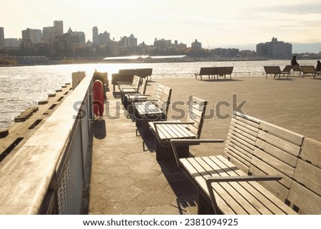 Sun shining on wooden benches on Pier 15 with the Brooklyn skyline