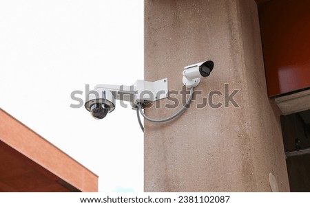 security camera perched high on a building's exterior, monitoring surroundings. Technology, surveillance, privacy, safety, urban living, modern security.