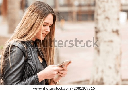 Attractive young woman texting on the street