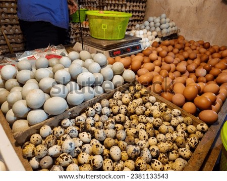 Quail eggs, chicken eggs and duck eggs in their respective boxes at a stall in a traditional market.