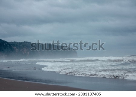 Misty beach with haze, big wave, and cliff