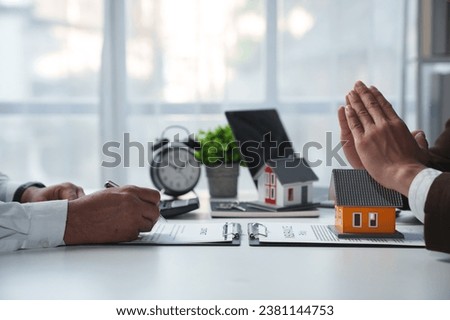 Businessman, lawyer, legal advisor sitting at work holding model home. Protect home, insurance, with business contract documents. Agreement on real estate project on desk at office