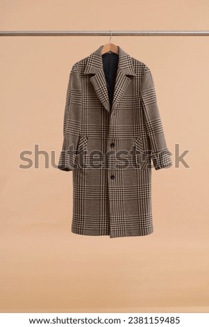 Striped wool coat hanging on clothes hanger on brow background.Close up. Royalty-Free Stock Photo #2381159485