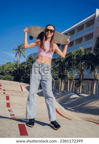 Happy young woman with skateboard enjoy longboarding at the skatepark