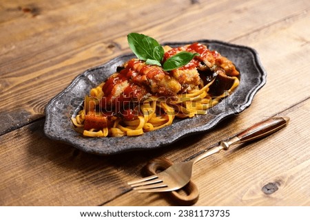 Pasta with ketchup. Basil cheese cutlet on top of it.