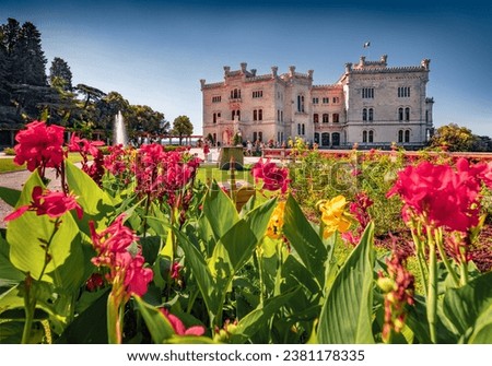 Superb summer view of Miramare Castle with blooming red tulip flowers on foreground. Impressive morning scene of Italy, Europe. Traveling concept background.