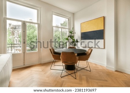 a living room with wood flooring and white walls, two large windows on the right side are lit by natural light Royalty-Free Stock Photo #2381193697