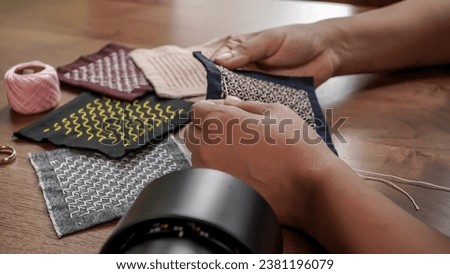 Hands sewing handkerchiefs on a wooden background. Hand crafted sahiko Japanese embroidery.  Royalty-Free Stock Photo #2381196079