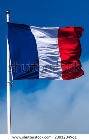 French tricolor flag fluttering with strong wind and blue sky