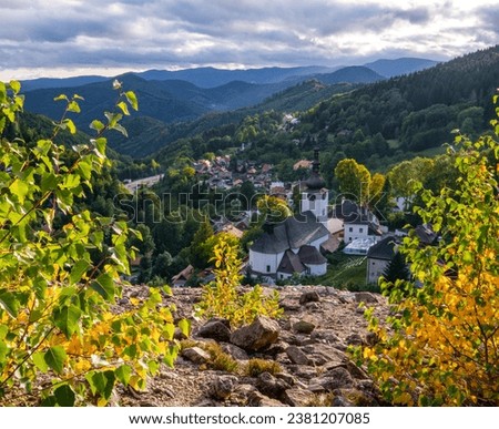 Village Spania Dolina. Fall in Slovakia. Old mining village. Historic church in Spania dolina. Autumn colored trees at sunset. Royalty-Free Stock Photo #2381207085
