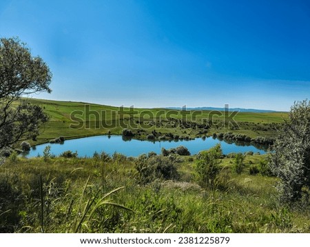 A scenic lake view in the province of Çorum in Turkey. The lake has a peaceful tranquility with the green areas around it. Royalty-Free Stock Photo #2381225879