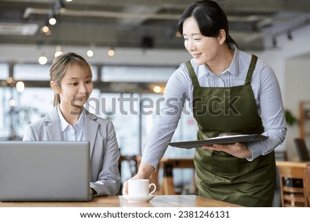 Asian female clerk working at a cafe Royalty-Free Stock Photo #2381246131