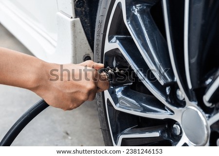 Close-Up Of Hand holding inflator for car tyre pressure measurement Royalty-Free Stock Photo #2381246153