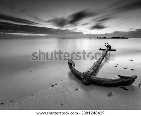 Old anchor lies on the beach long exposure black and white