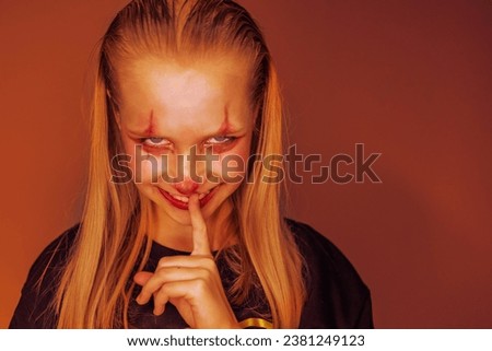 Girl with make up for Halloween on orange  background.