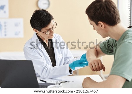 Portrait of mature female doctor inspecting patient with skin rash during consultation in dermatology clinic Royalty-Free Stock Photo #2381267457