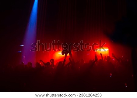 Silhouettes in front of an orange lit stage - rock music concert