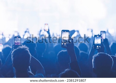 People taking pictures and recording at the big concert. Close-up shot. Streaming at the concert. High quality photo