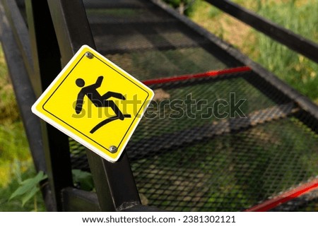 Yellow slippery warning sign on the metal curve bridge