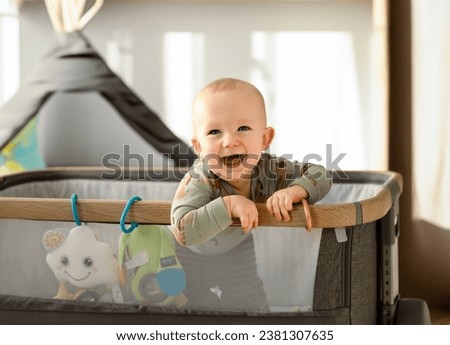 Laughing little boy in a travel cot Royalty-Free Stock Photo #2381307635