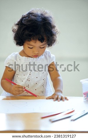 Young girl, drawing and classroom for creative development, education growth in kindergarten. Child, daycare and table pencils artwork for learning play in school or paper crayons, kid craft or color