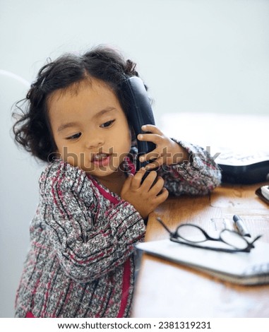 Playing, talking and a child on a telephone for communication, pretend work and cute. Sitting, house and a girl, kid or a baby speaking on a landline phone for play, imagination or discussion Royalty-Free Stock Photo #2381319231